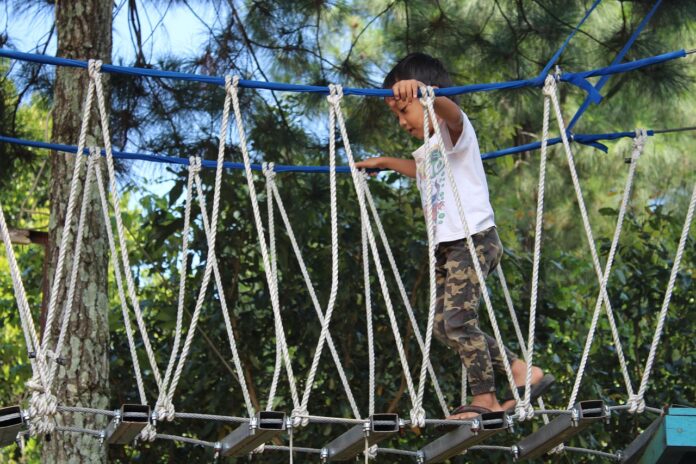 a child playing on a mini suspension bridge